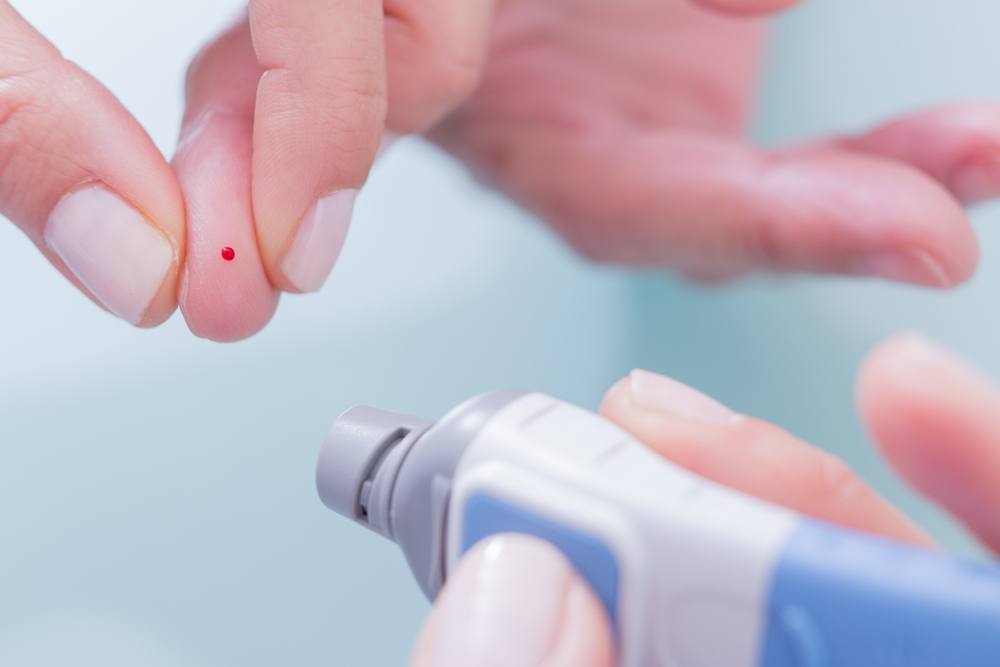 Blutzuckermessgeräte mit einem Finger samt leicht blutenden Einstich